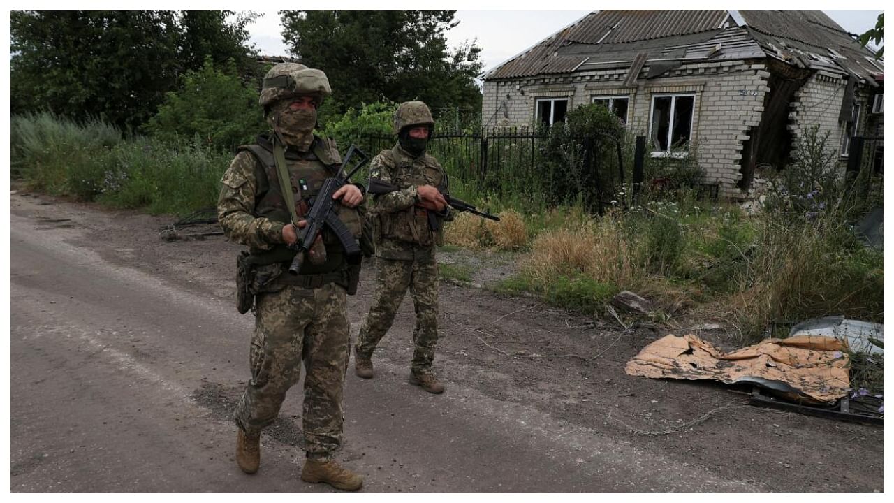 Ukrainian servicemen walk past a house damaged by a Russian military strikes in the village of Vremivka, amid Russia's attack on Ukraine, near a front line in Donetsk region, Ukraine July 8, 2023. Credit: Reuters Photo