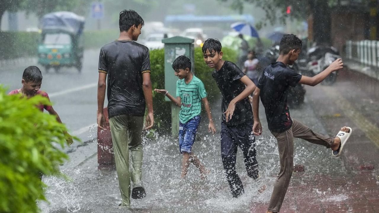 Children enjoy on a waterlogged street amid heavy monsoon rains, in New Delhi. Credit: PTI Photo