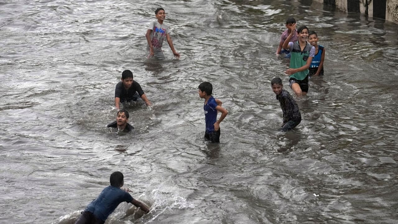 Children play on a waterlogged road amid monsoon rains, in New Delhi, Sunday, July 9, 2023. Credit: PTI Photo