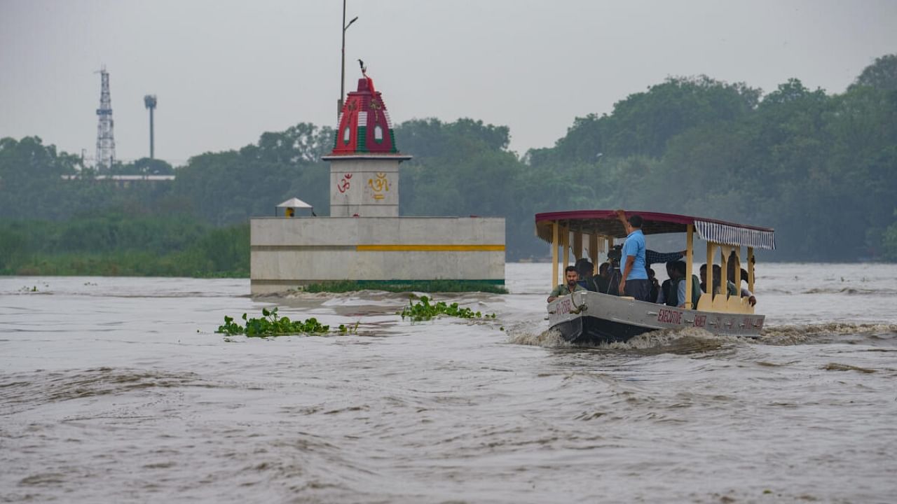 People take ride on a boat in Yamuna river after heavy monsoon rains, in New Delhi, Monday, July 10, 2023. Credit: PTI Photo