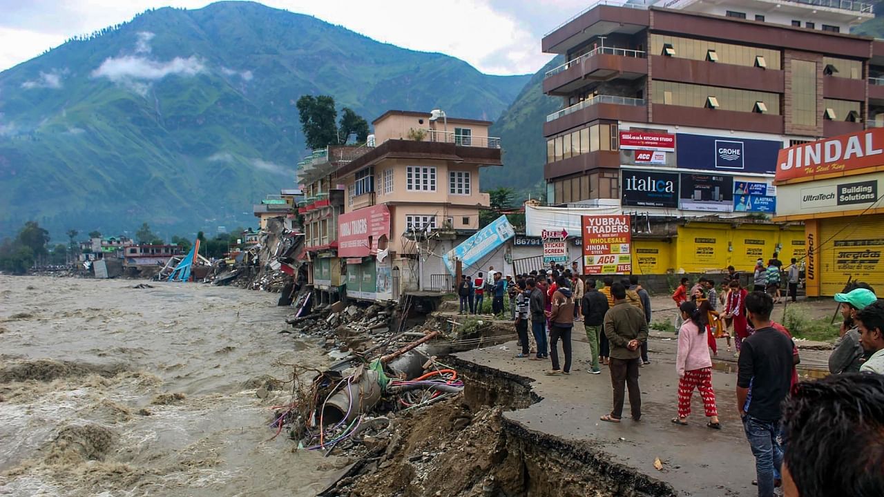 Locals walk along the eroded riverbank damaged by the swollen Beas river following heavy monsoon rains, in Kullu, Tuesday, July 11, 2023. Credit: PTI Photo