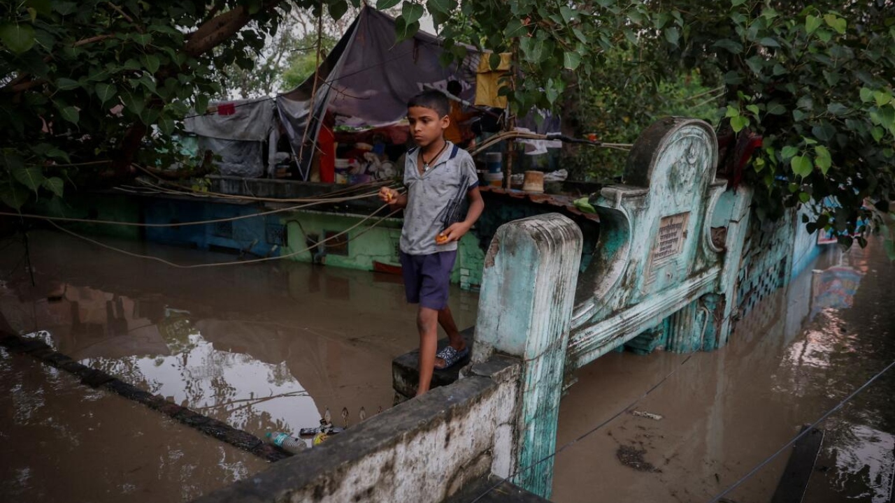 A boy walks on a wall of his flooded house after a rise in the water level of river Yamuna in New Delhi. Credit: Reuters Photo