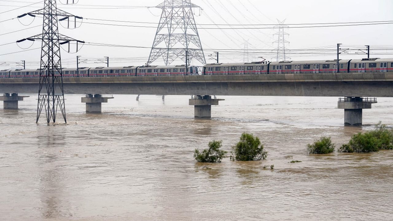 A Delhi Metro train moves slowly over the bridge spanning the swollen Yamuna river, in New Delhi, Thursday, July 13, 2023. Credit: PTI Photo