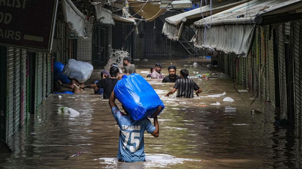 Locals wade through the flooded Monastery market following monsoon rains, in New Delhi, Wednesday, July 12, 2023. Credit: PTI Photo