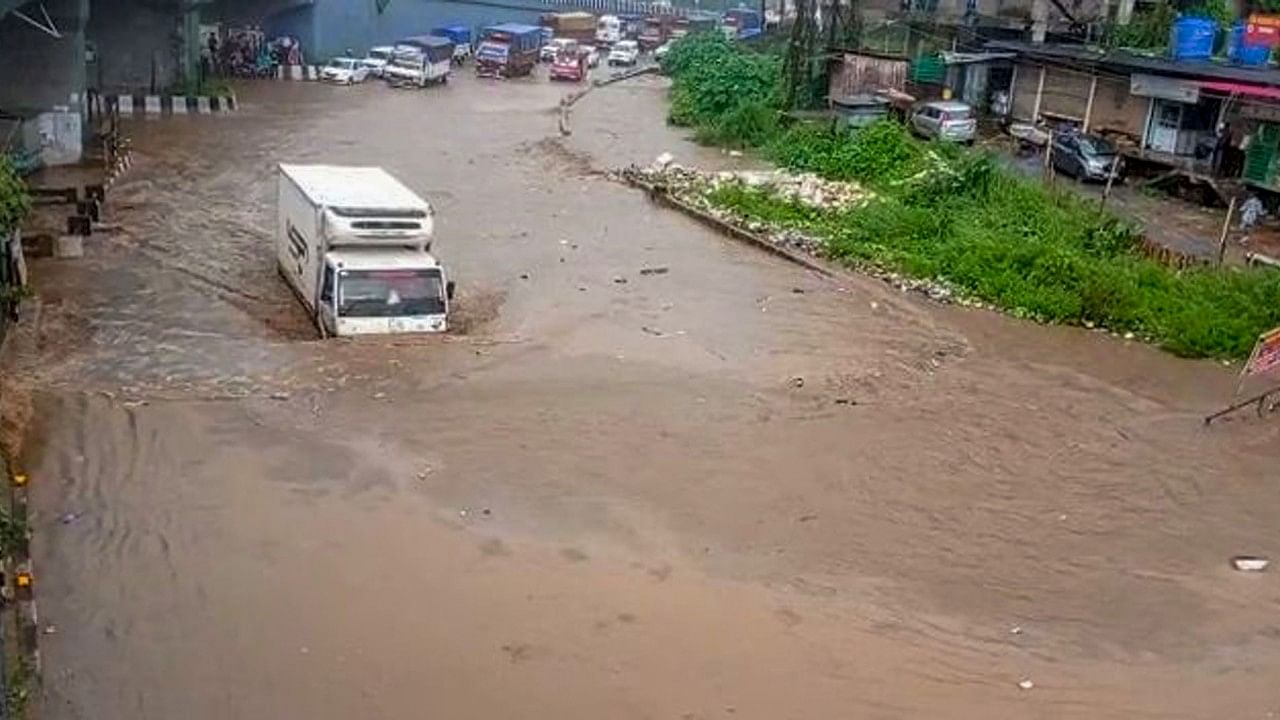 Vehicles move through the waterlogged National Highway 27 following monsoon rains. Credit: PTI Photo