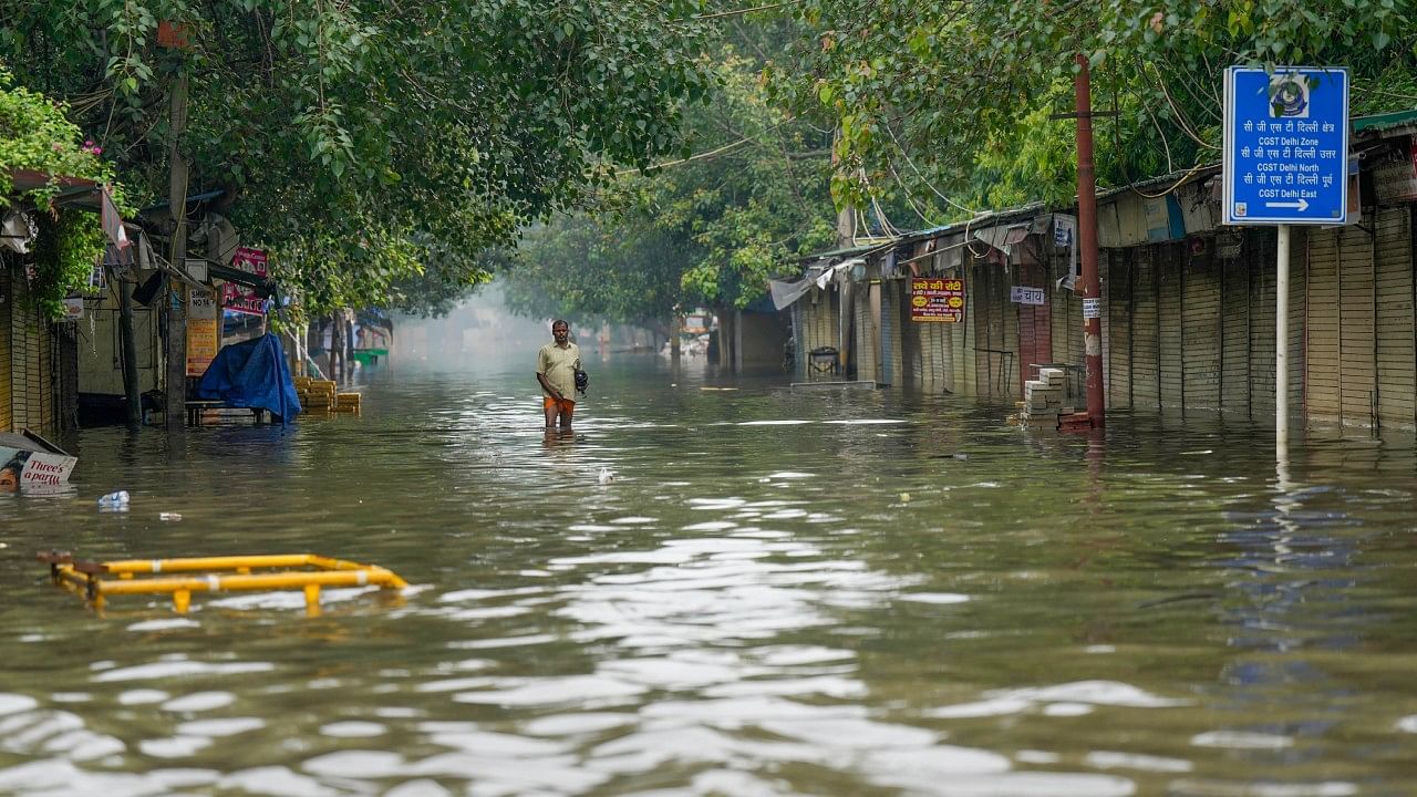 A man wades through a waterlogged road as the swollen Yamuna river inundates nearby areas. Credit: PTI Photo