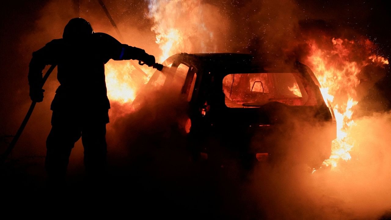 A French firefighter works to extinguish a burning car during the fifth day of protests following the death of Nahel, a 17-year-old teenager killed by a French police officer in Nanterre during a traffic stop, in Tourcoing, France.  Credit: Reuters Photo