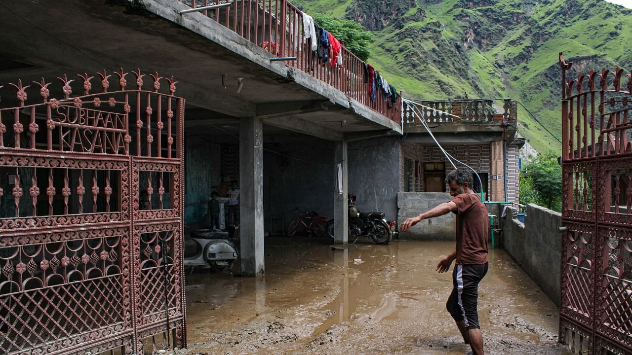 A resident walks through debris outside a building following a cloud-burst at Jilla village in Kullu district, Monday, July 17, 2023. Credit: PTI Photo