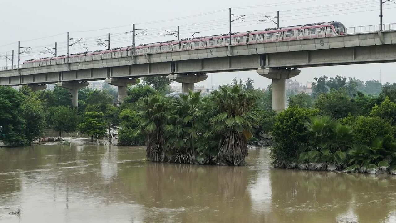 A metro train moves slowly as the Yamuna river swollen up, at Mayur Vihar in New Delhi. Credit: PTI Photo