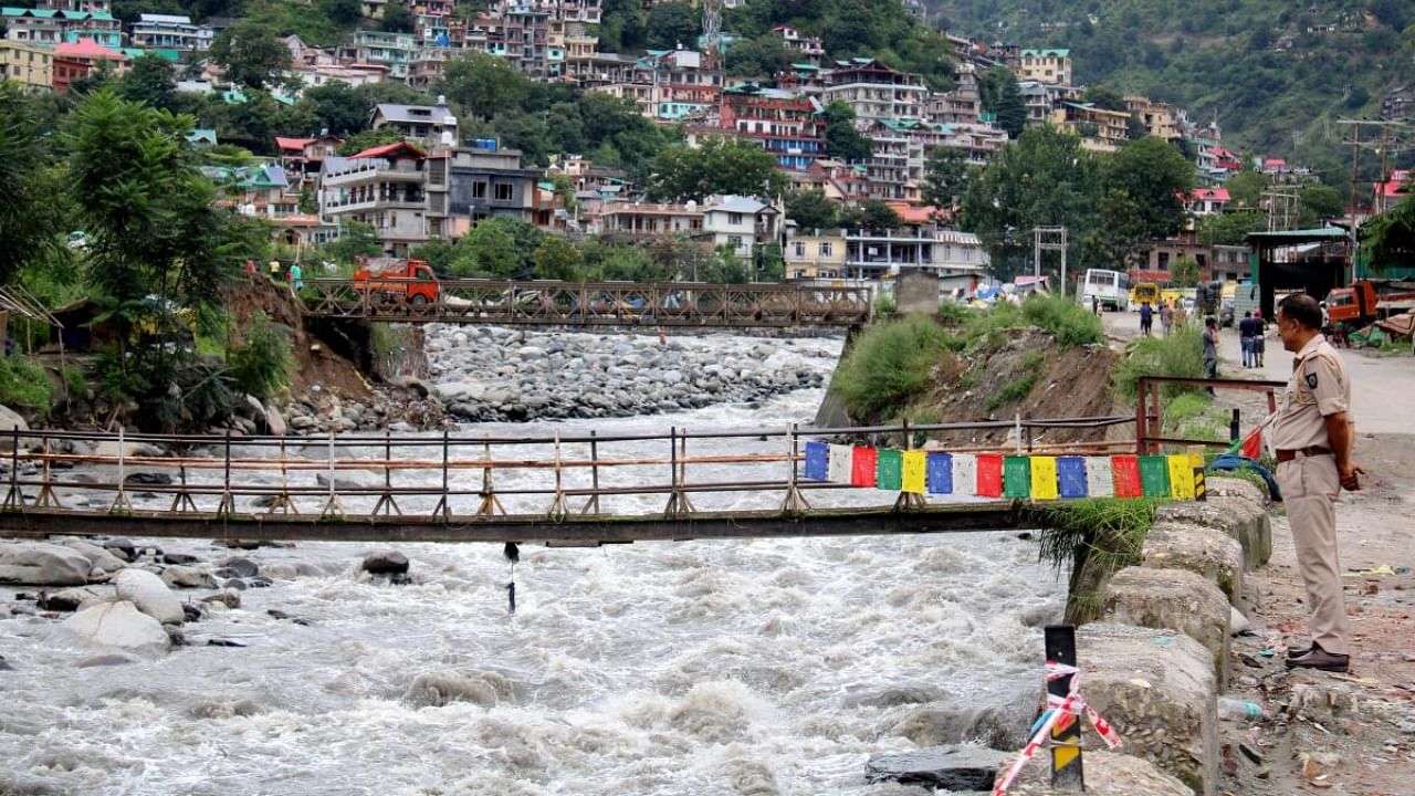 A policeman watches the flow of Sarwari river during monsoon season, in Kullu. Credit: PTI Photo