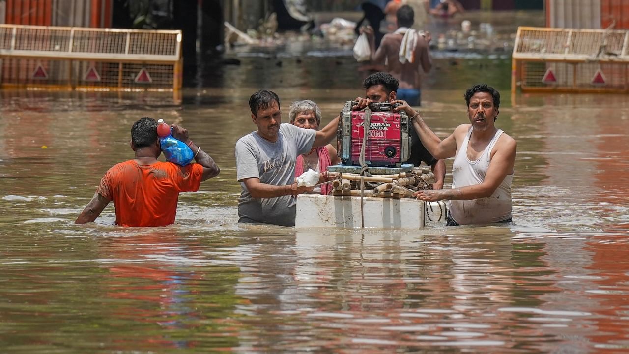People pass through a waterlogged street after the Yamuna river inundated the naerby areas, at Yamuna Bazar in New Delhi. Credit: PTI Photo