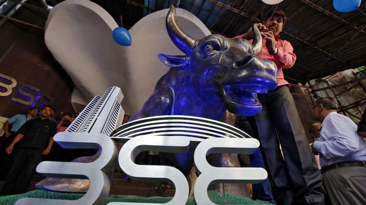 A man ties a balloon to the horns of a bull statue at the entrance of the Bombay Stock Exchange (BSE) while celebrating the Sensex index rising to over 30,000, in Mumbai, India April 26, 2017. Credit: Reuters Photo