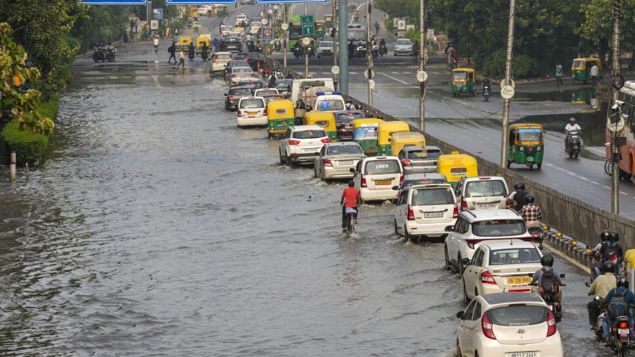 Vehicles pass through a waterlogged road after recent heavy monsoon rains, at ITO in New Delhi. Credit: PTI Photo