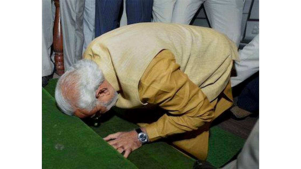 Prime Minister-elect Narendra Modi bends down on the steps of the main entrance of Parliament as a sign of respect as he arrives for the BJP parliamentary party meeting at Central Hall in New Delhi on Tuesday. PTI Photo