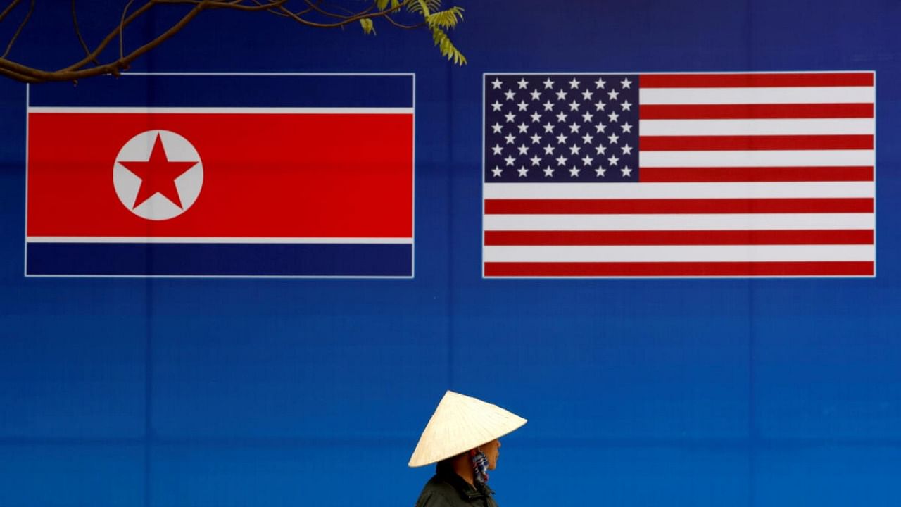 A person walks past a banner showing North Korean and US flags. Credit: Reuters Photo