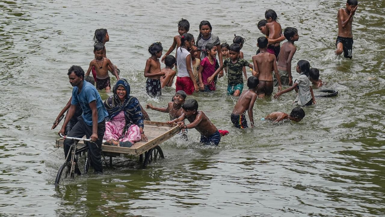 Flood affected people wade through the floodwaters of the swollen Yamuna river near Mayur Vihar after heavy monsoon rainfall, in New Delhi, Wednesday, July 19, 2023. Credit: PTI Photo