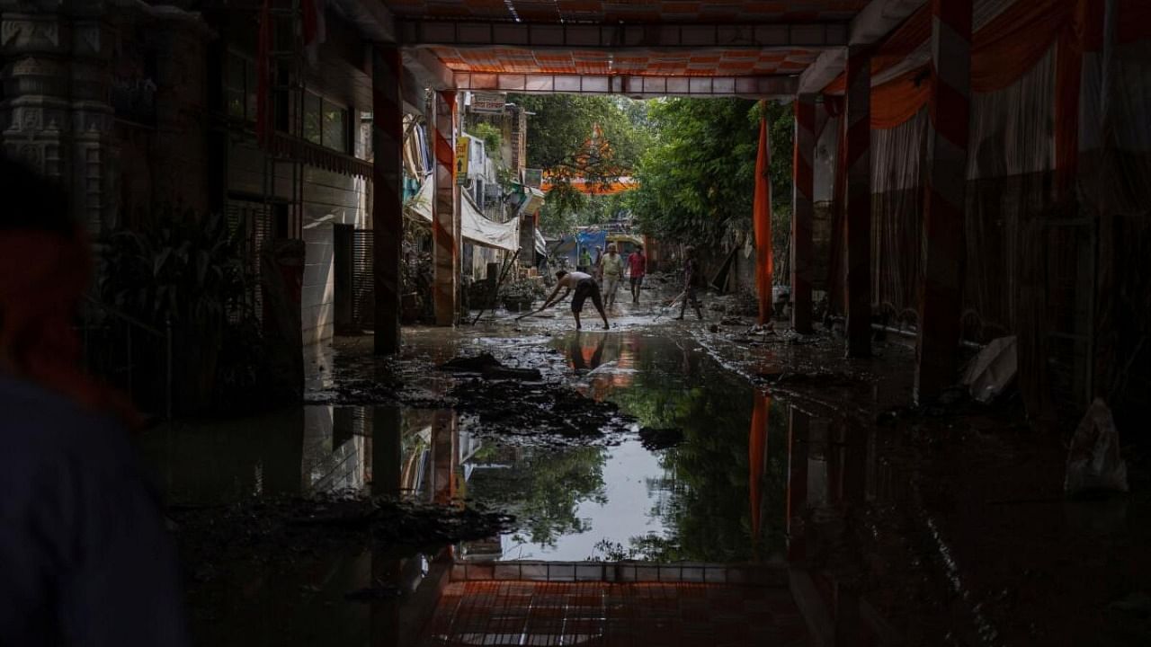 People clean the mud outside their house after flood water recedes from a residential area that was flooded by the overflowing of the river Yamuna following heavy rains, in New Delhi, India, July 17, 2023. Credit: Reuters Photo