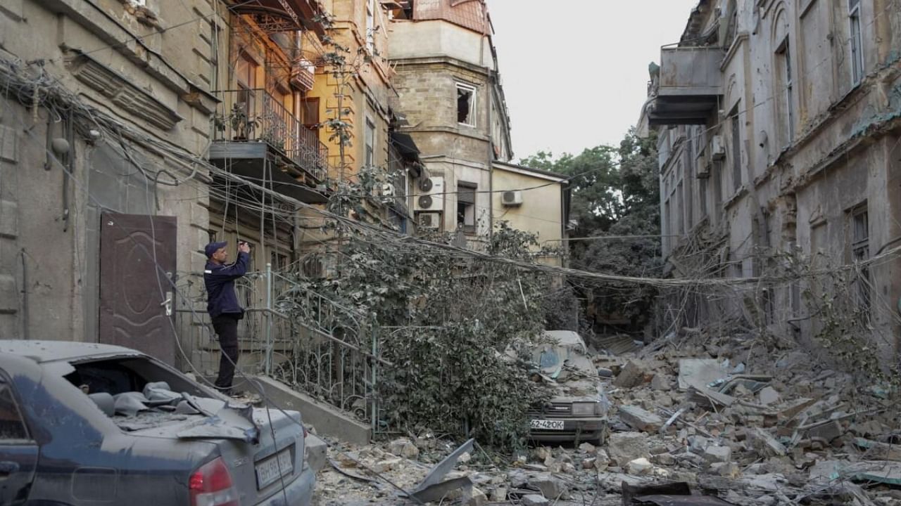 A rescuer takes a picture of a residential building damaged during a Russian missile strike. Credit: Reuters Photo