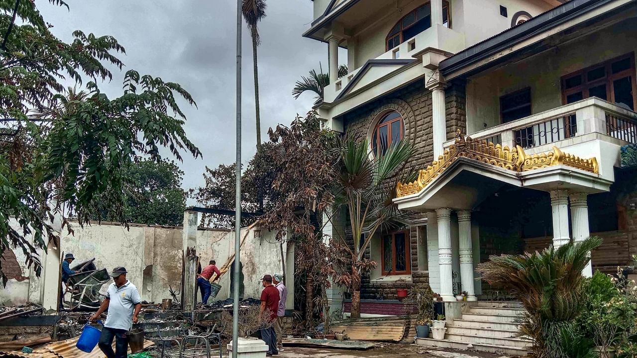 Workers attempt to salvage burnt items at Union Minister of State for External Affairs R K Ranjan Singh’s residence in Imphal, Friday, June 16, 2023. Credit: PTI Photo