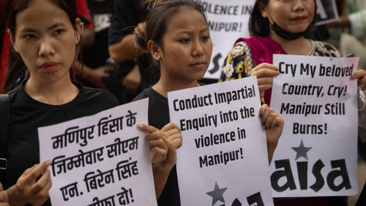 Protestors hold placards as they attend a protest against the alleged sexual assault of two tribal women in Manipur. Credit: Reuters Photo