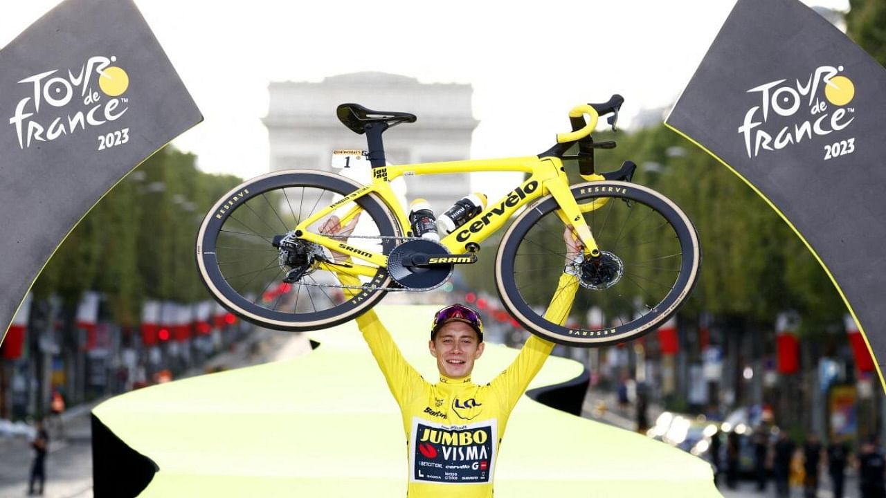Jumbo–Visma's Jonas Vingegaard lifts his bike on the podium wearing the overall leader's yellow jersey after winning the Tour de France. Credit: Reuters Photo