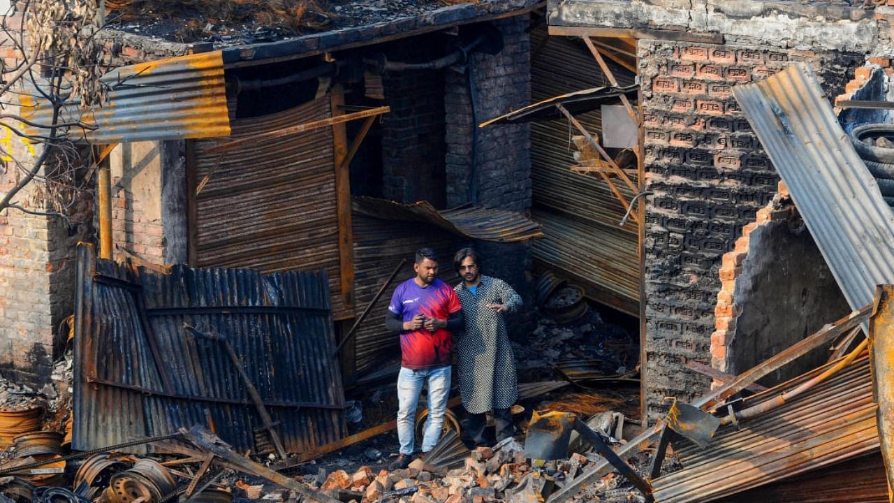 Shop owners look at the charred remains of the tyre market in riot affected Gokulpuri area of North East Delhi. Credit: PTI File Photo