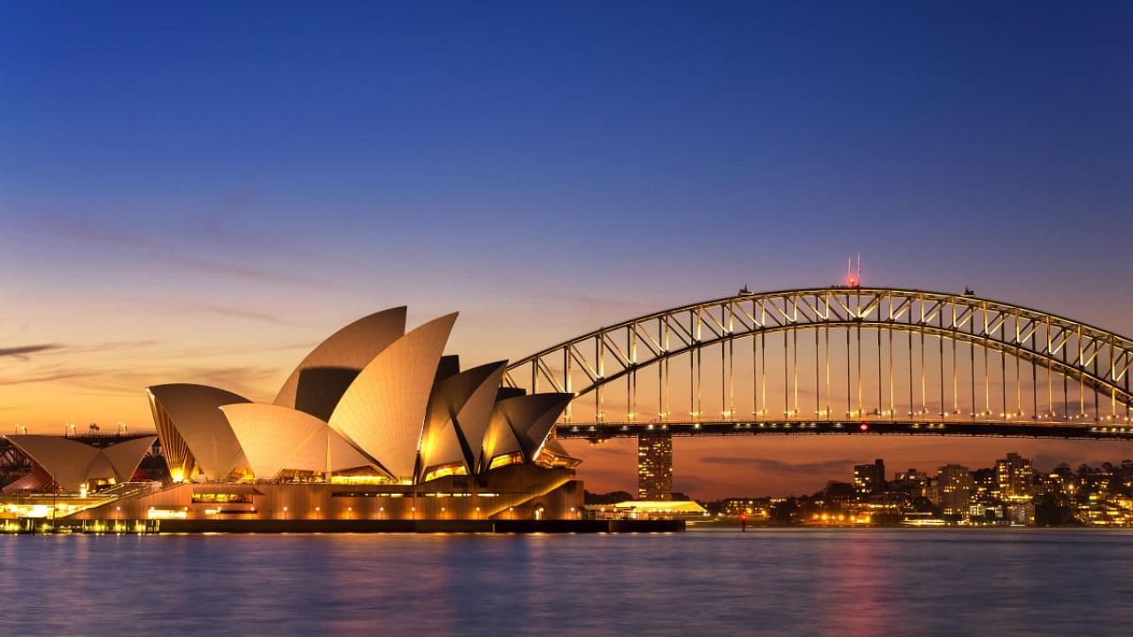 Beautiful Opera house view at twilight time with vivid sky and illumination on the bridge.Opera House with the Sydney Harbour in the background. Getty image