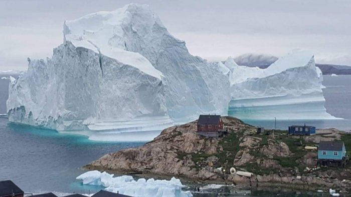 A giant iceberg seen behind a settlement in Greenland. Credit: Reuters Photo