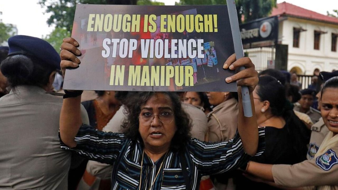 A demonstrator holds up a placard, as police officers detain others during a protest against the sexual assault of two tribal women in Manipur, in Ahmedabad, July 23, 2023. Credit: Reuters Photo
