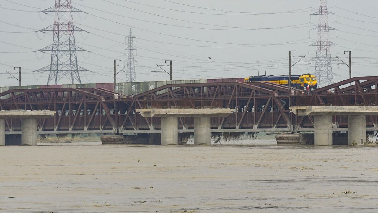 A goods train crosses the Old Railway Bridge even as the River Yamuna continued to flow above the danger level, in New Delhi, Tuesday, July 25, 2023. Credit: PTI Photo