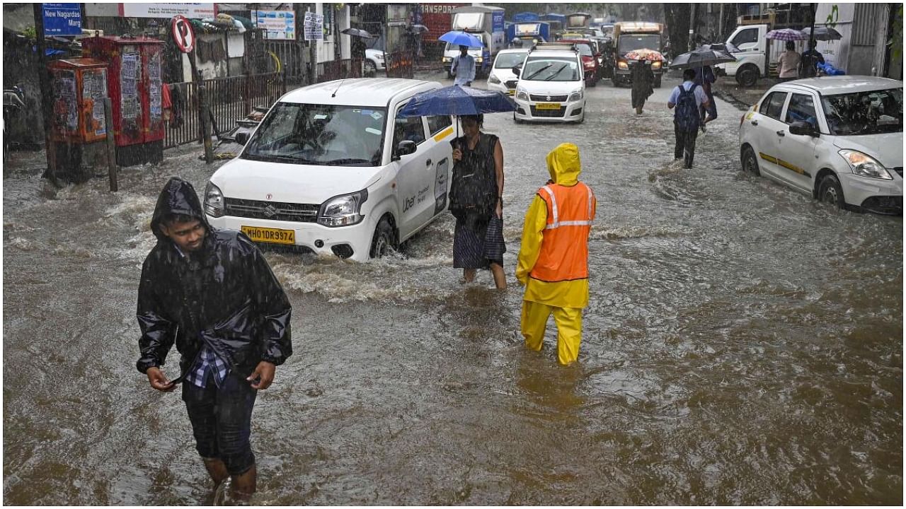 Mumbai: People pass through a waterlogged street after incessant monsoon rainfall, in Mumbai, Wednesday, July 26, 2023. Credit: PTI Photo