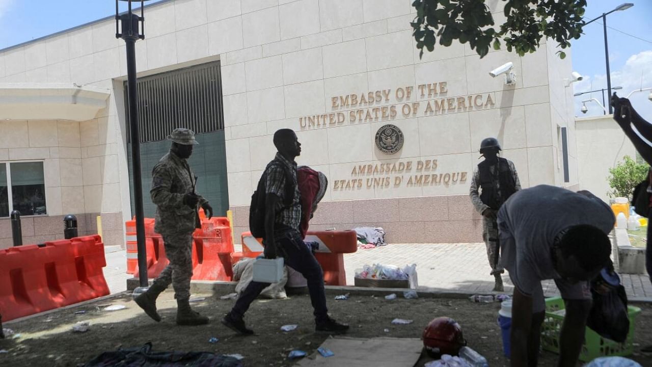 A man carries his belongings after officers of the Haitian National Police fired tear gas to clear a camp of people escaping the threat of armed gangs, in front of the US Embassy, in Port-au-Prince, Haiti July 25, 2023. Credit: Reuters Photo