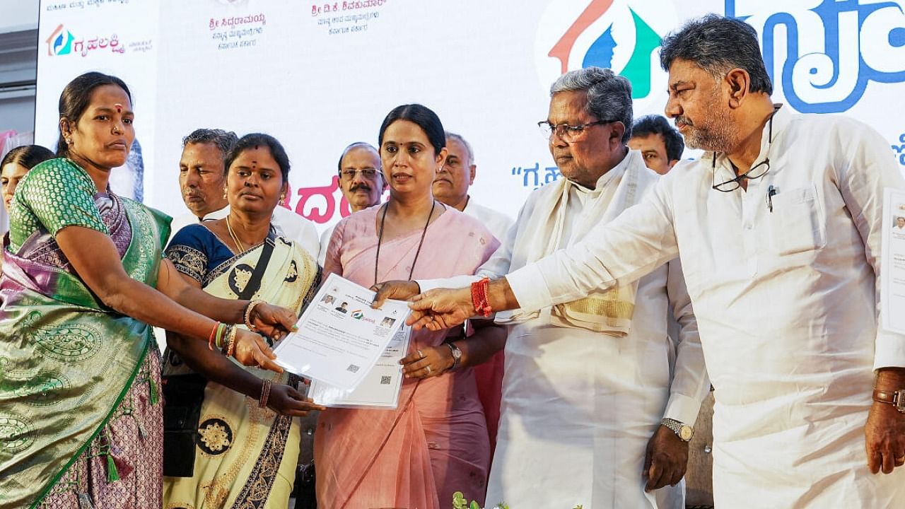 Karnataka CM Siddaramaiah and Deputy CM D K Shivakumar hand over certificates of Gruha Lakshmi scheme during its launch at Vidhanasoudha, in Bengaluru. Credit: PTI File Photo