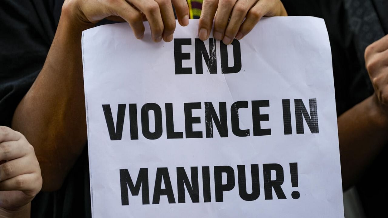 A protester holds a placard during a protest against the ongoing ethnic violence in Manipur. Credit: PTI Photo