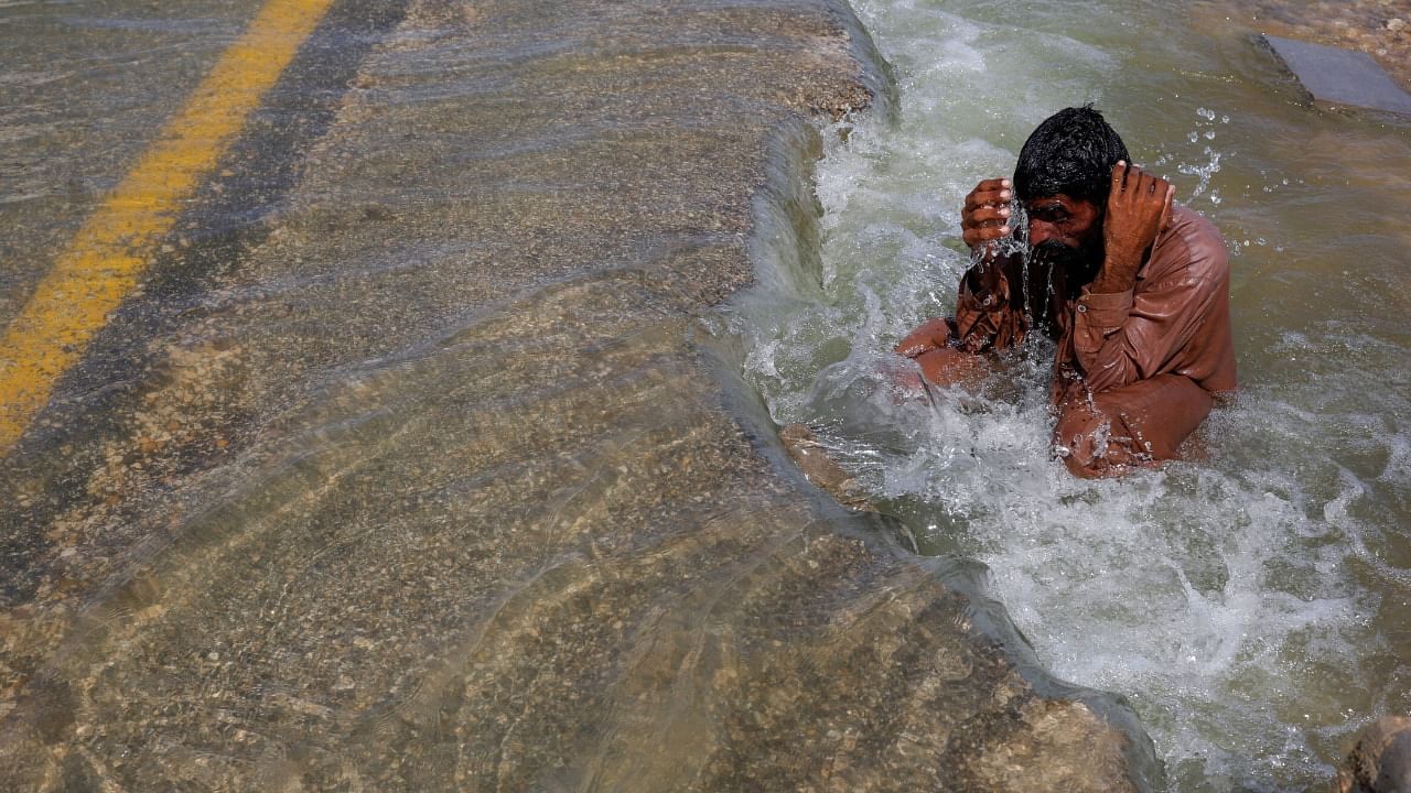Pakistani man displaced by floods cools off on an inundated highway. Credit: Reuters Photo