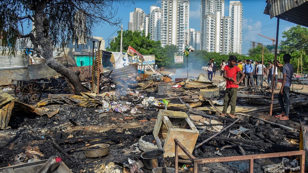 A worker inspects burnt items at a shop which was set ablaze by miscreants in a fresh case of communal violence after Monday's attack on a VHP procession in adjoining Nuh district, at Sector 67 area in Gurugram, Tuesday, August 1, 2023. Credit: PTI Photo