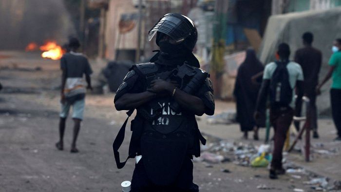 A riot police member holds his weapon as people walk during clashes with supporters of Senegal opposition leader Ousmane Sonko after he was sentenced to prison. Credit: Reuters Photo