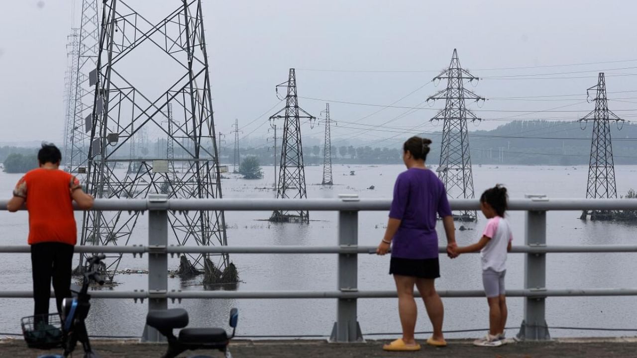 <div class="paragraphs"><p>People look at electricity pylons in a flooded river after remnants of Typhoon Doksuri brought rains and floods in Beijing, China, August 2, 2023. </p></div>