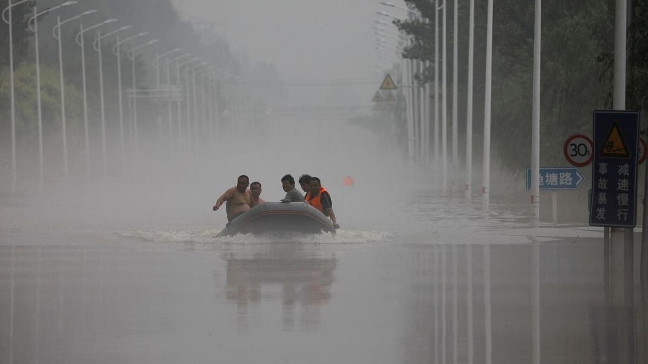 People ride a boat through a flooded road after the rains and floods brought by remnants of Typhoon Doksuri, in Zhuozhou, Hebei province, China August 3, 2023. Credit: Reuters Photo