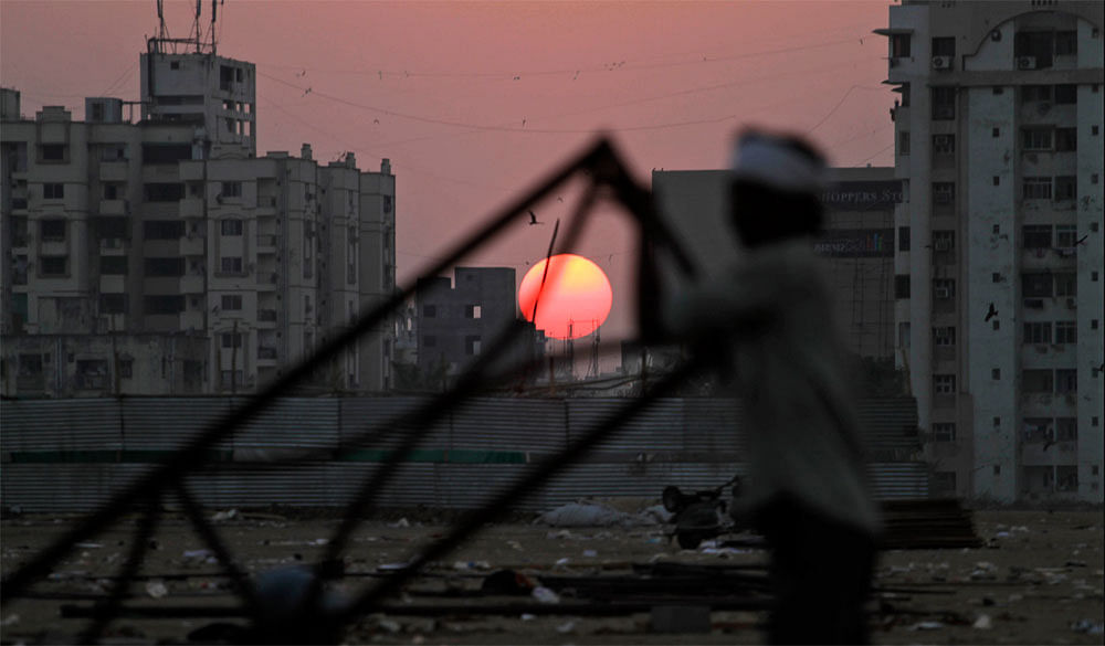 A worker dismantles a temporary structure erected for a function, as the sun sets in Ahmedabad, Friday, Feb. 3, 2012.AP Photo