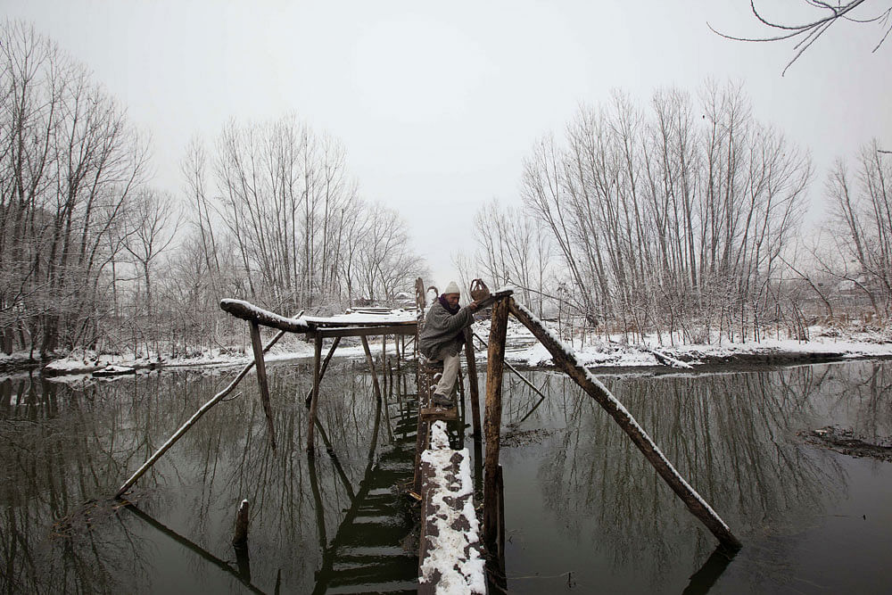 An elderly Kashmiri man makes his way through a foot bridge after a fresh snowfall in Srinagar, India, Wednesday, Feb. 15, 2012. The Jammu-Srinagar highway remained closed to traffic for the third day due to the heavy snowfall in the region, accordin...