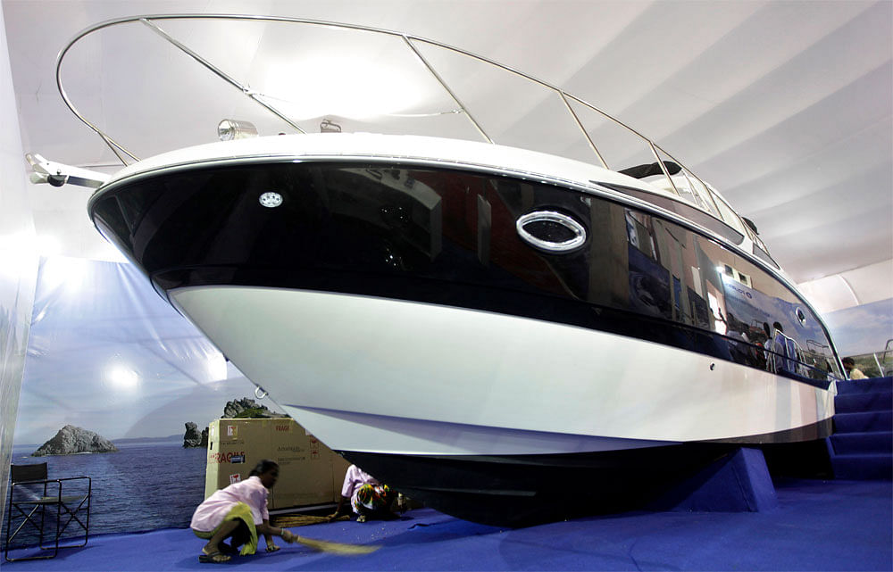 A worker sweeps the floor under a boat displayed at the Mumbai International Boat Show in Mumbai on Thursday. AP Photo