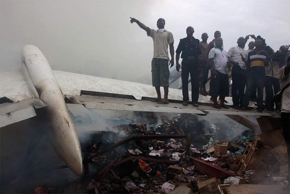People gather at the site of a plane crash in Lagos, Nigeria, Sunday,  June 3, 2012. A commercial airliner crashed into a densely populated  neighborhood in Nigeria's largest city on Sunday, killing all 153 people  on board and others on the ground i...
