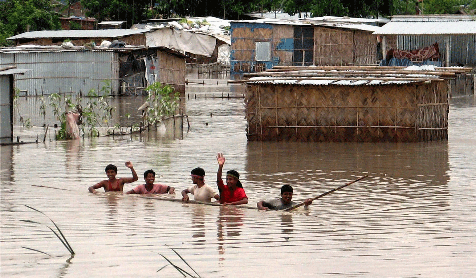 A family moves for safer areas as they wade through flooded Fulbari village near Siliguri on Sunday. PTI Photo