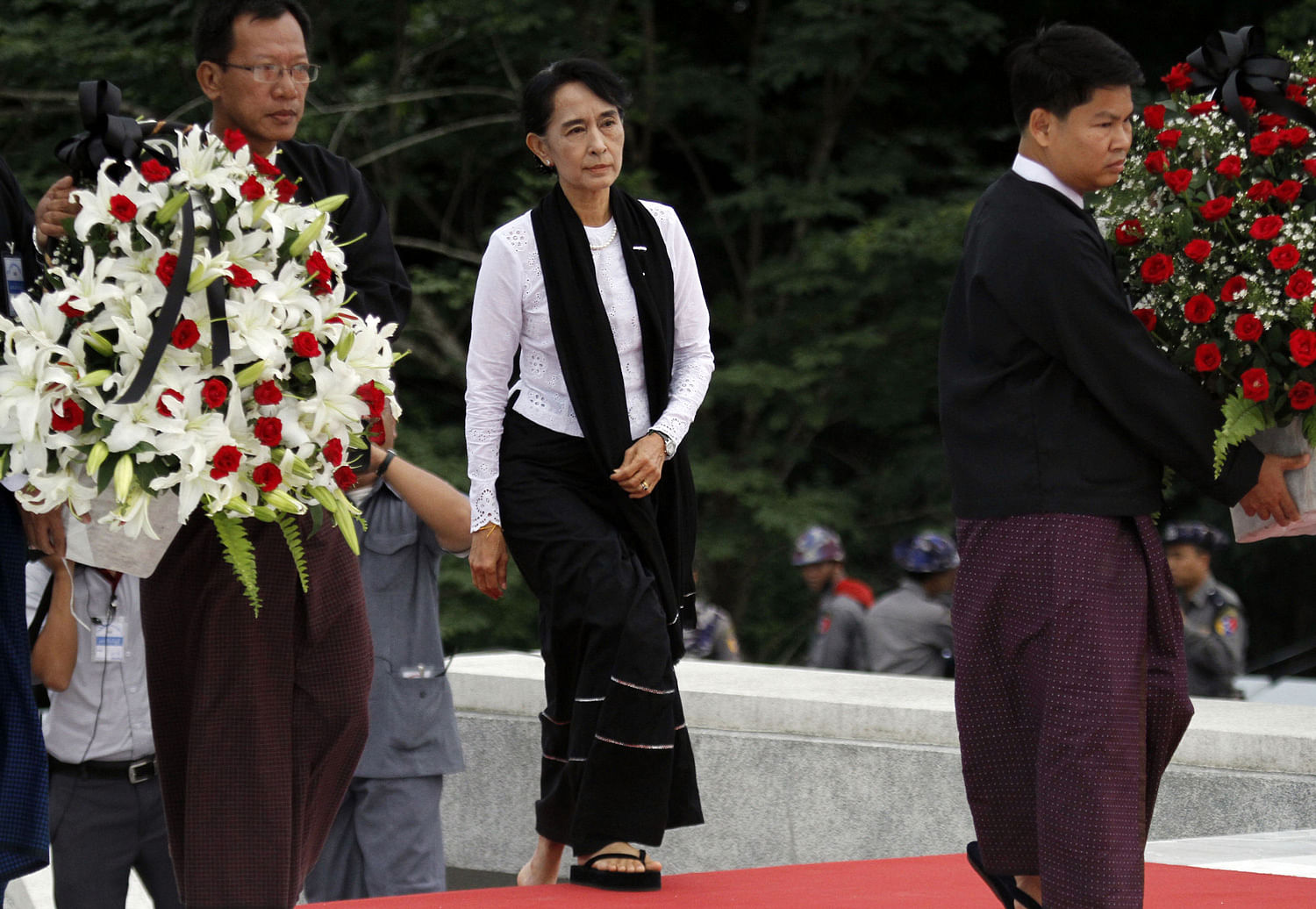 Myanmar opposition leader Aung San Suu Kyi, center, arrives to lay flowers at the tomb of her late father Gen. Aung San during a ceremony to mark the 65th anniversary of his 1947 assassination, at the Martyrs' Mausoleum in Yangon, Myanmar on Thursday...