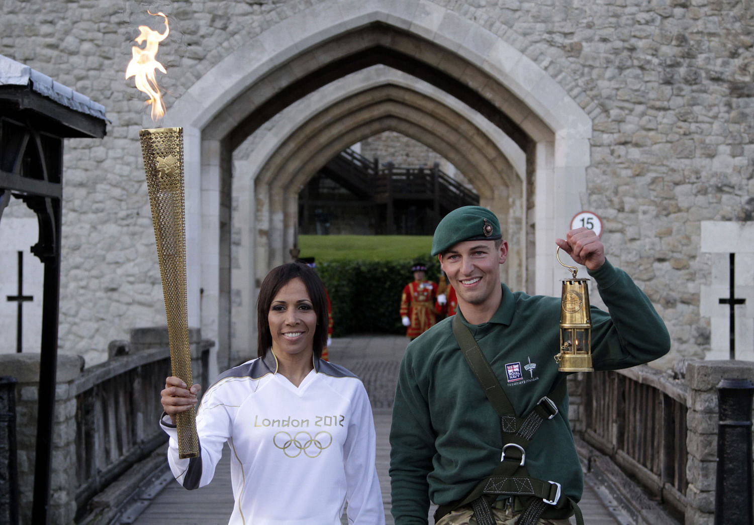 British retired champion Dame Kelly Holmes, left, poses for the photographers with the Olympic flame, along with British Royal Marine Martyn Williams, 23, right, who abseiled from a Sea King helicopter, with the lantern with the Olympic flame strappe...