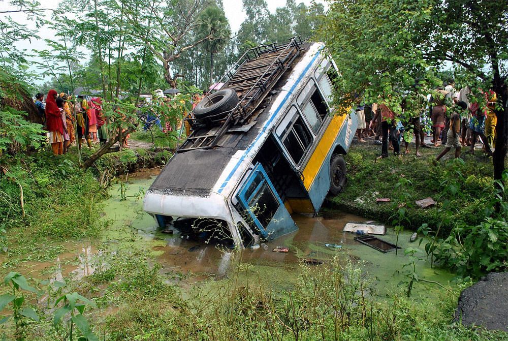 Malda: People looking at the ill-fated private bus which collided with a Taxi on the state highway at Jamtala under Gazole police station in Malda district on Saturday. PTI Photo