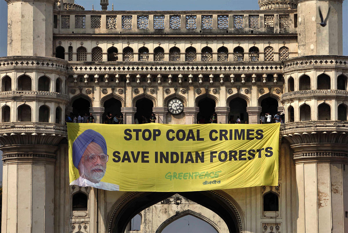Greenpeace activists hang a banner with a photo of Indian Prime Minister Manmohan Singh atop the Charminar monument in Hyderabad,  India, Monday, Oct. 8, 2012. The activists were protesting against India hosting the U.N. summit on biodiversity even a...