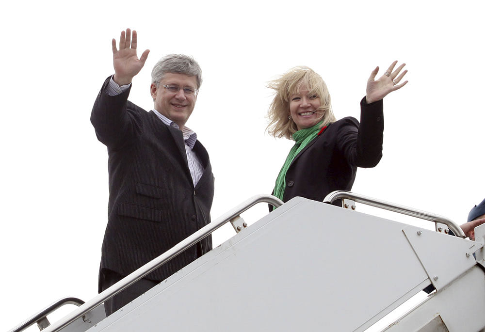 Canadian Prime Minister Stephen Harper and his wife Laureen wave while boarding their plane before departing for India to boost bilateral trade and economic ties, in Ottawa, November 3, 2012. REUTERS