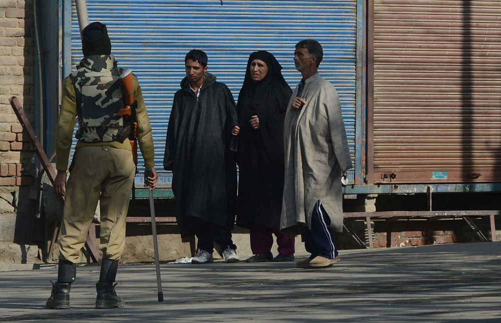 An Indian paramilitary soldier stops a Kashmiri family as they walk along a street during a second day of indefinite curfew in Srinagar on November 30, 2012. The curfew comes following clashes between groups of Shia and Sunni Muslims in the restive H...